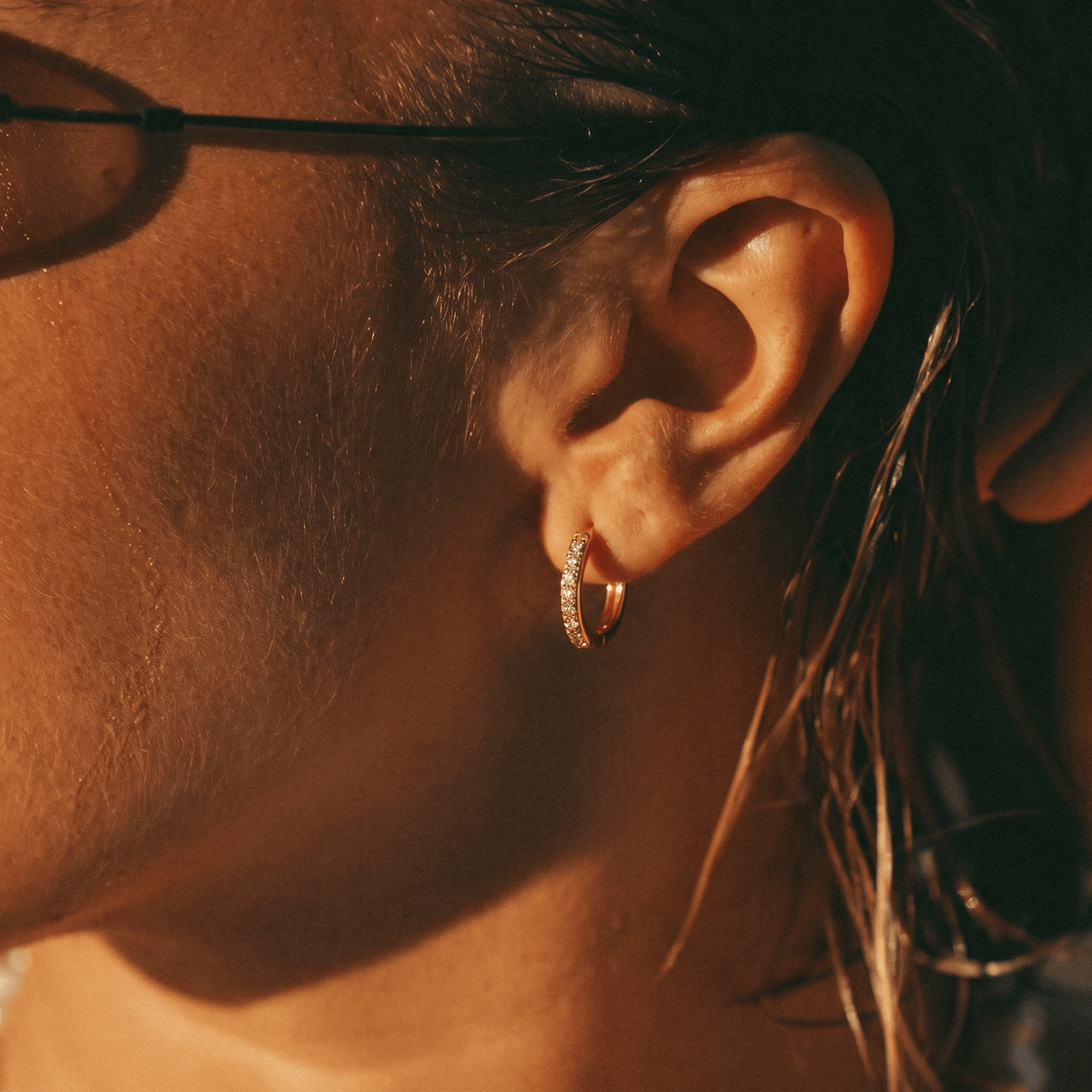 Pendientes de aro dorados con pedrería, vistos en la oreja