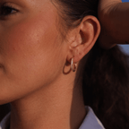 Pendientes de aro dorados con pedrería, detalle en la oreja