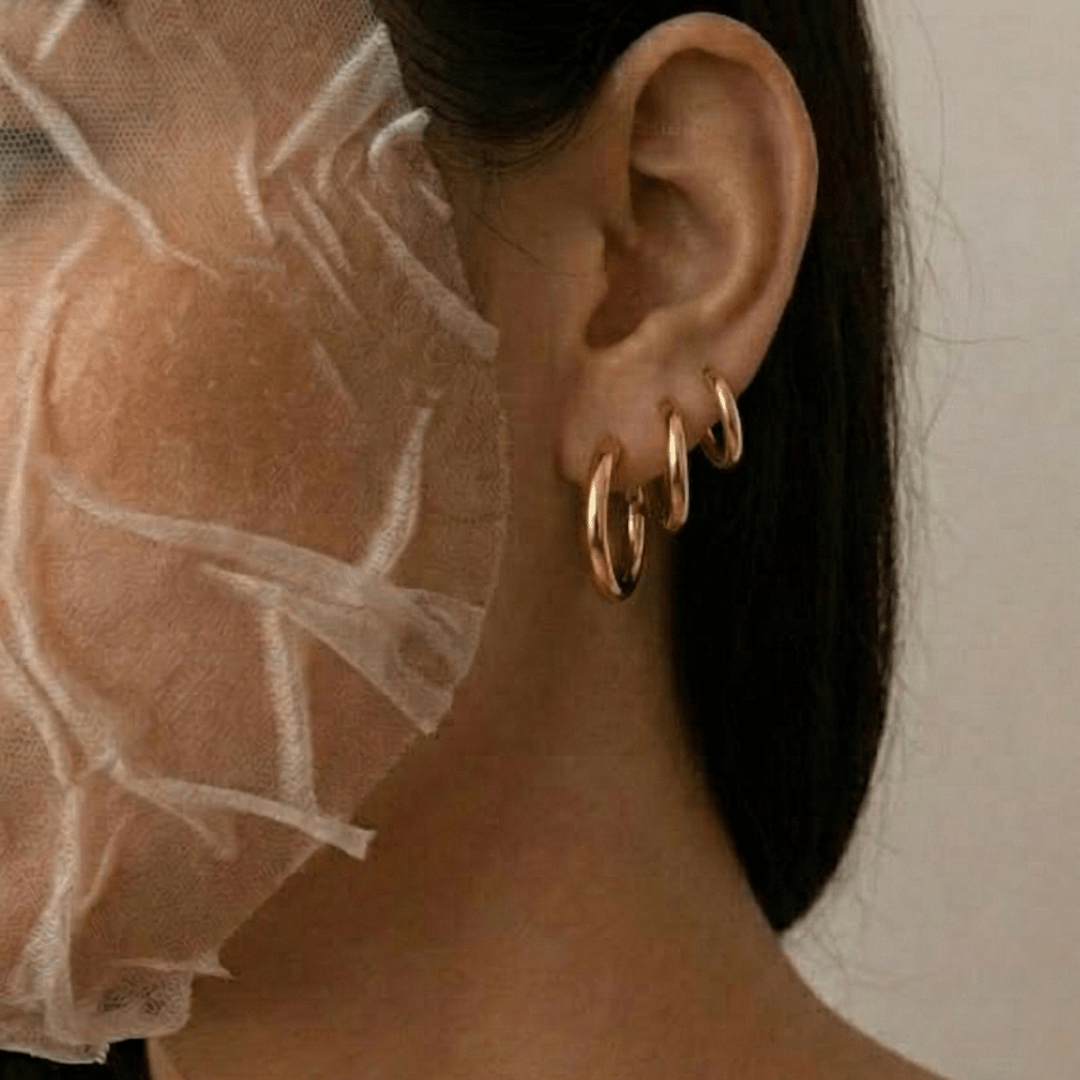 Set de 3 aros tipo argolla dorados en la oreja, con el cabello al lado