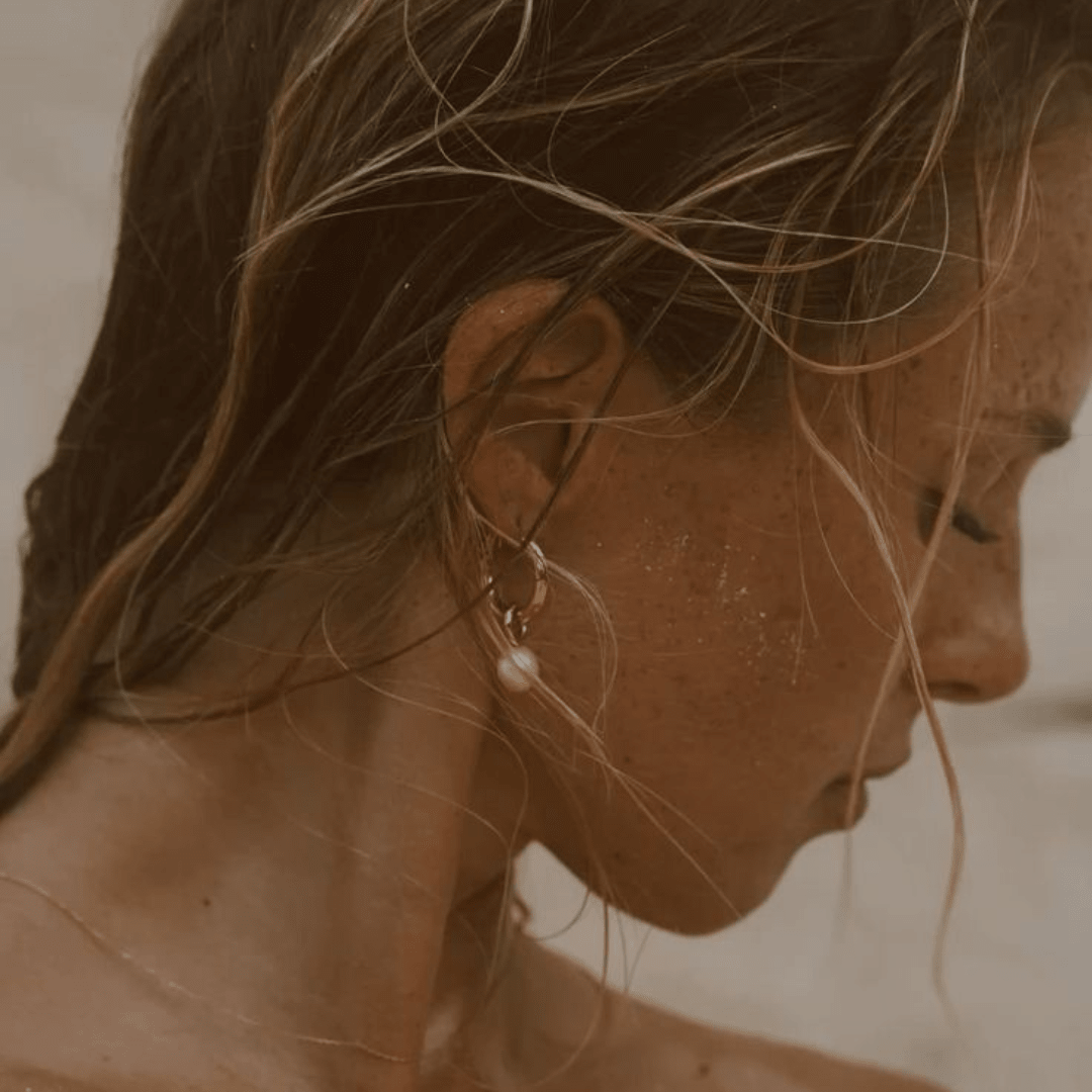Pendientes de argolla con perla blanca; vista lateral sobre el cabello