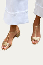 Sandalias Vela de tiras abiertas doradas con tacón medio y pulsera al tobillo.