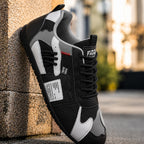 Zapatillas retro negras y grises con paneles blancos y cordones negros.