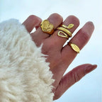 Anillos serpiente dorados sobre la palma, motivos de escamas y espirales