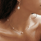 Aros dorados con perla blanca; detalle en el cuello y la oreja