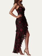 Vestido elegante negro con estampado floral rojo, volantes asimétricos y abertura; vista lateral.