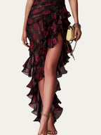 Vestido elegante negro con estampado floral rojo; detalle de volantes y abertura lateral.