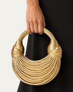 Bolso esencial tipo aro dorado con asas trenzadas y estructura de anillos