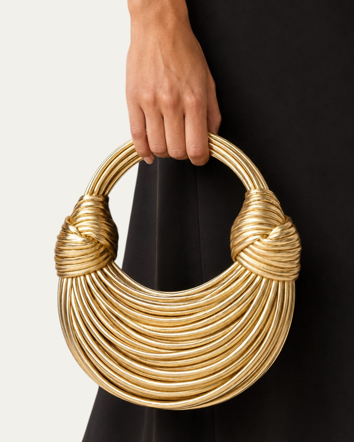 Bolso esencial tipo aro dorado con asas trenzadas y estructura de anillos