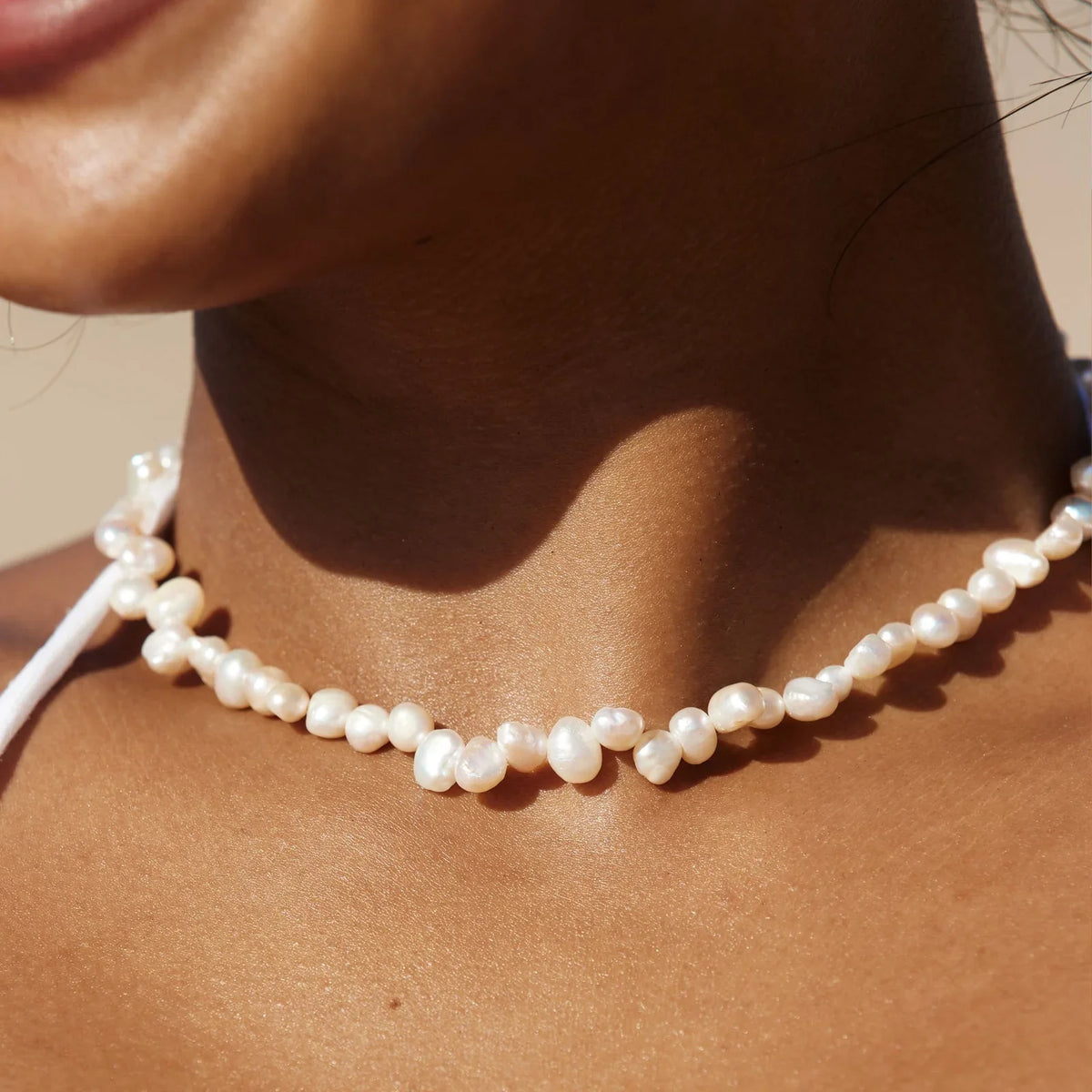 Choker de perlas blancas en el cuello, cuentas redondas y brillo suave.