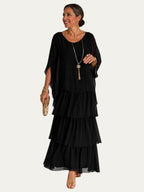 Vestido largo negro con volantes en capas y mangas tipo capa sueltas, escote redondo.