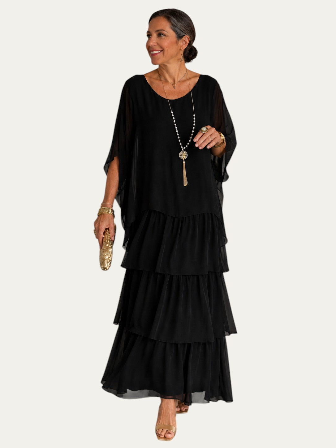 Vestido largo negro con volantes en capas y mangas tipo capa sueltas, escote redondo.