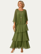 Vestido largo verde con volantes escalonados y manga tipo capa, escote redondo.