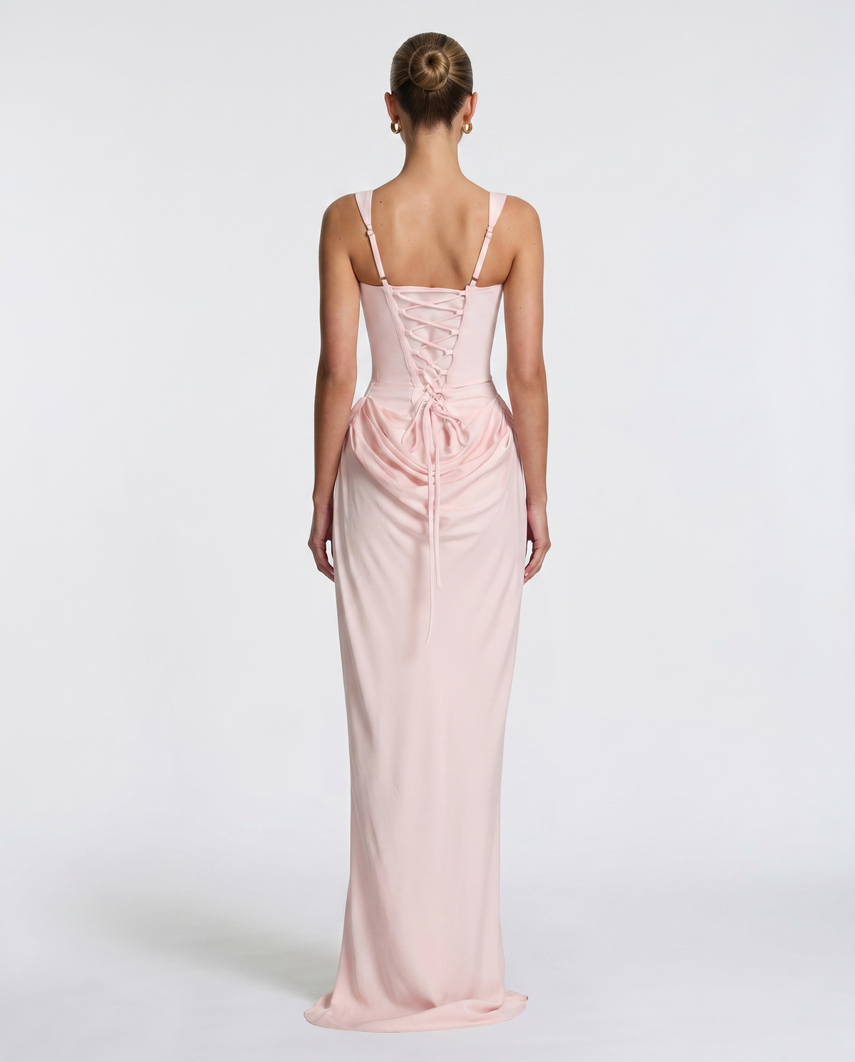 Vestido maxi rosa claro; espalda con tirantes y fruncido con cordones decorativos.