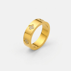 Anillo dorado con detalles de trébol y piedras brillantes en el lateral