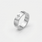 Anillo plateado con detalles de trébol y piedras brillantes en el lateral