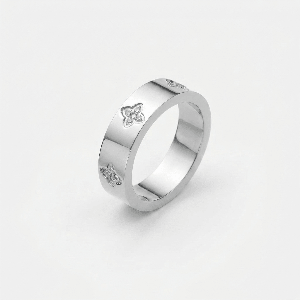 Anillo plateado con detalles de trébol y piedras brillantes en el lateral
