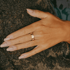Anillo dorado con tréboles y piedras brillantes sobre la mano