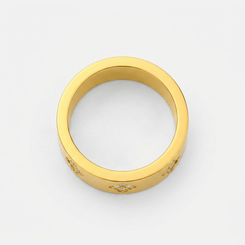 Anillo dorado liso con decoración de tréboles y piedras pequeñas en el borde