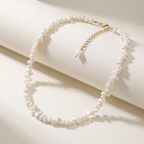 Choker de perlas blancas con cierre dorado, sobre fondo claro.