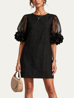 Vestido negro corto de organza con mangas abullonadas y puños de flores