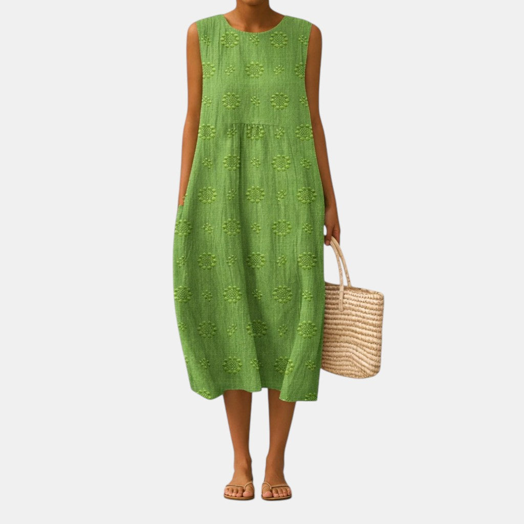 Vestido midi verde sin mangas con tejido ligero y patrón floral repetido, caída holgada.