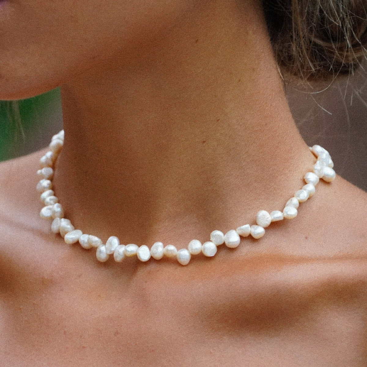 Choker de perlas blancas de varias cuentas, ajustado al cuello.
