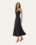 Vestido midi negro de tirantes finos, corte entallado y falda amplia.